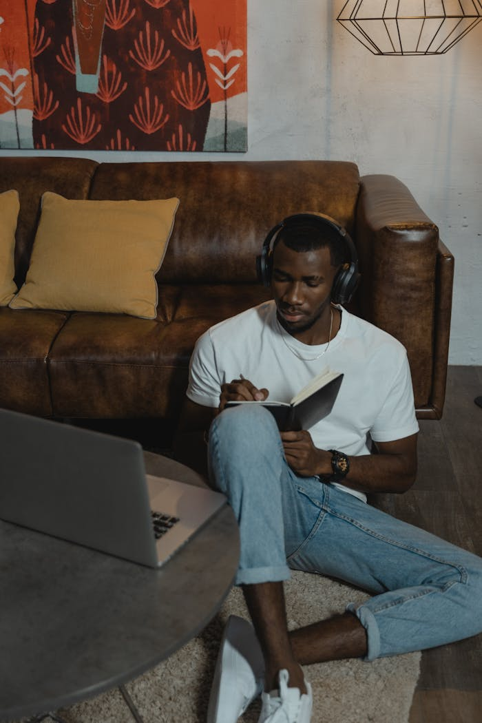 African American man studying online with laptop in cozy living room setting.